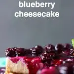 Sliced cheesecake topped with blueberry sauce and a sprig of mint against a grey background