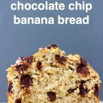 A loaf of chocolate chip banana bread on a sheet of brown baking paper against a grey background