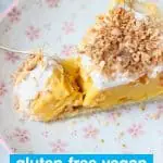 A slice of pie with yellow custard topped with white cream and toasted coconut on a white plate with pink flowers