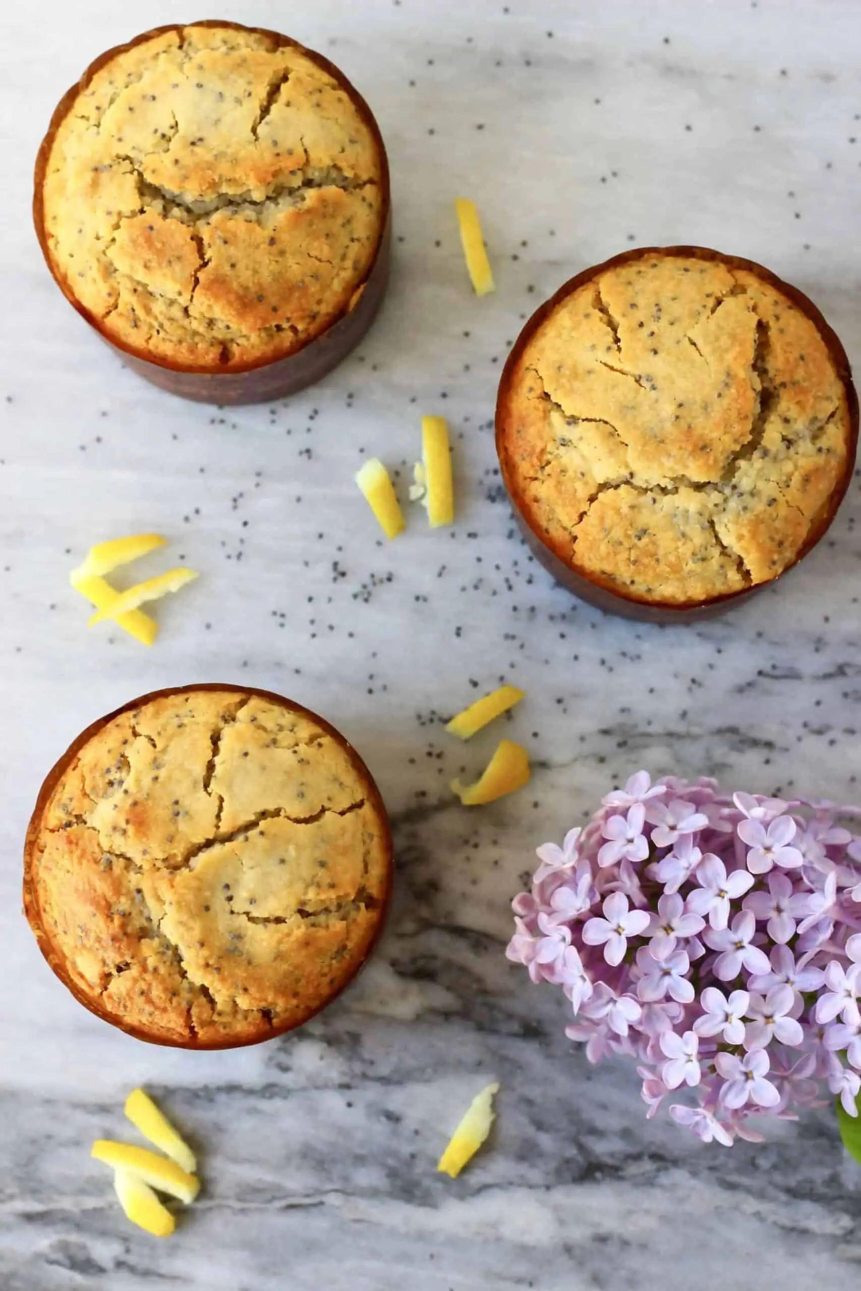 Three gluten-free vegan lemon poppy seed muffins in brown muffin cases 
