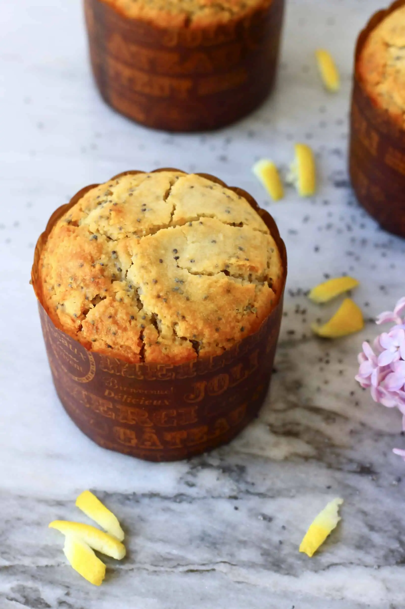 Three gluten-free vegan lemon poppy seed muffins in brown muffin cases