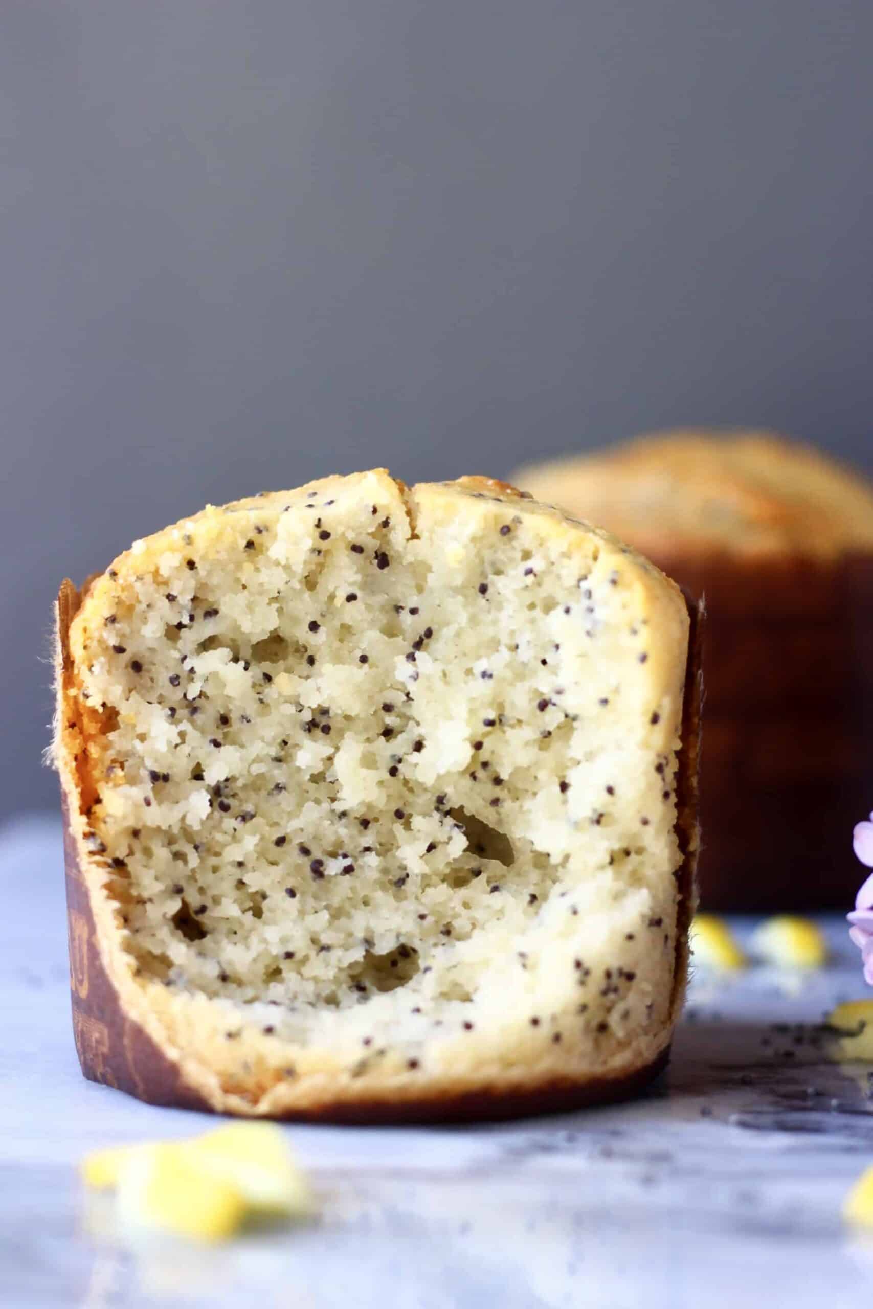 Un muffin de semillas de amapola de limón vegano sin gluten cortado por la mitad en una placa de mármol 