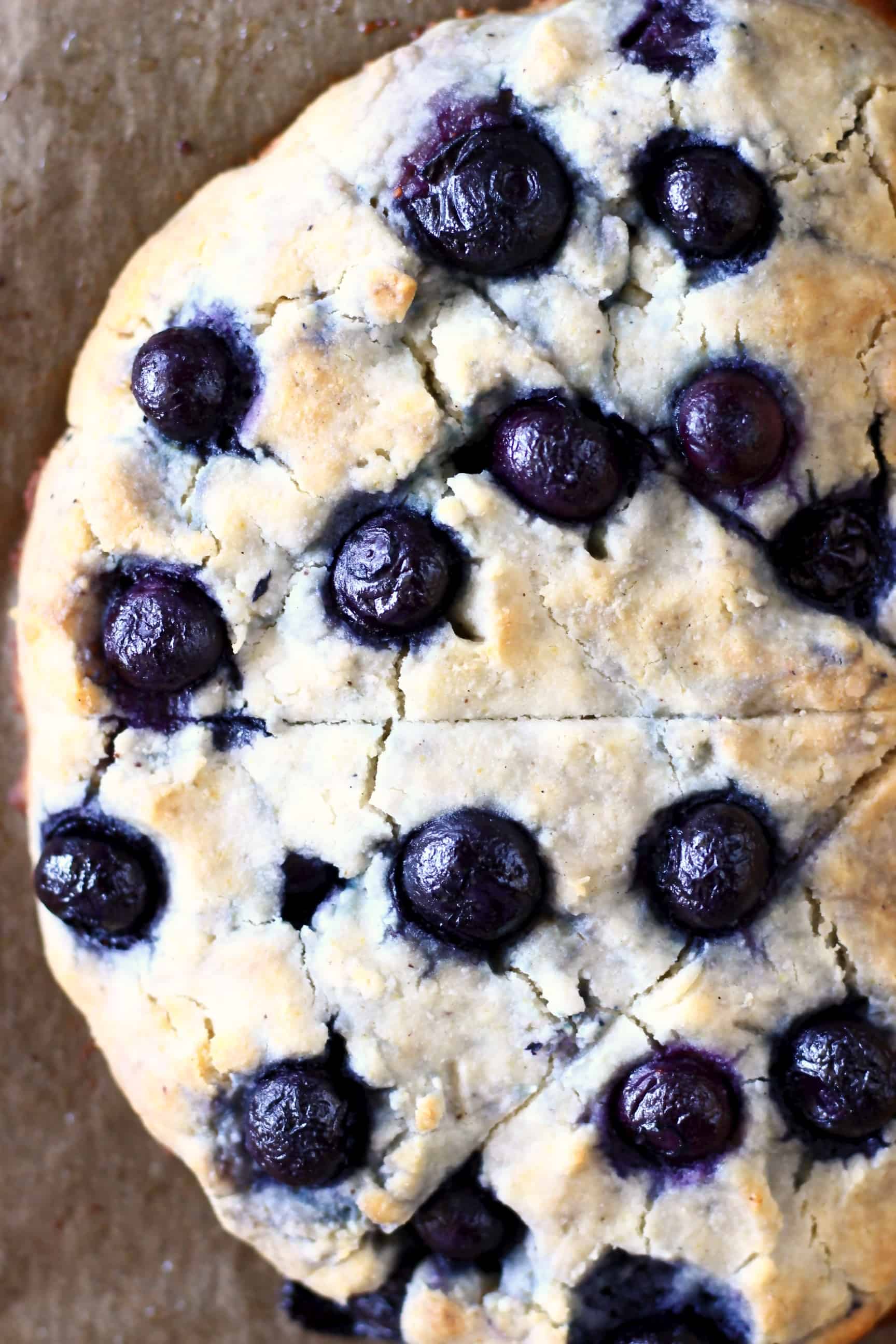 Four triangular gluten-free blueberry scones bunched together on a sheet of brown baking paper