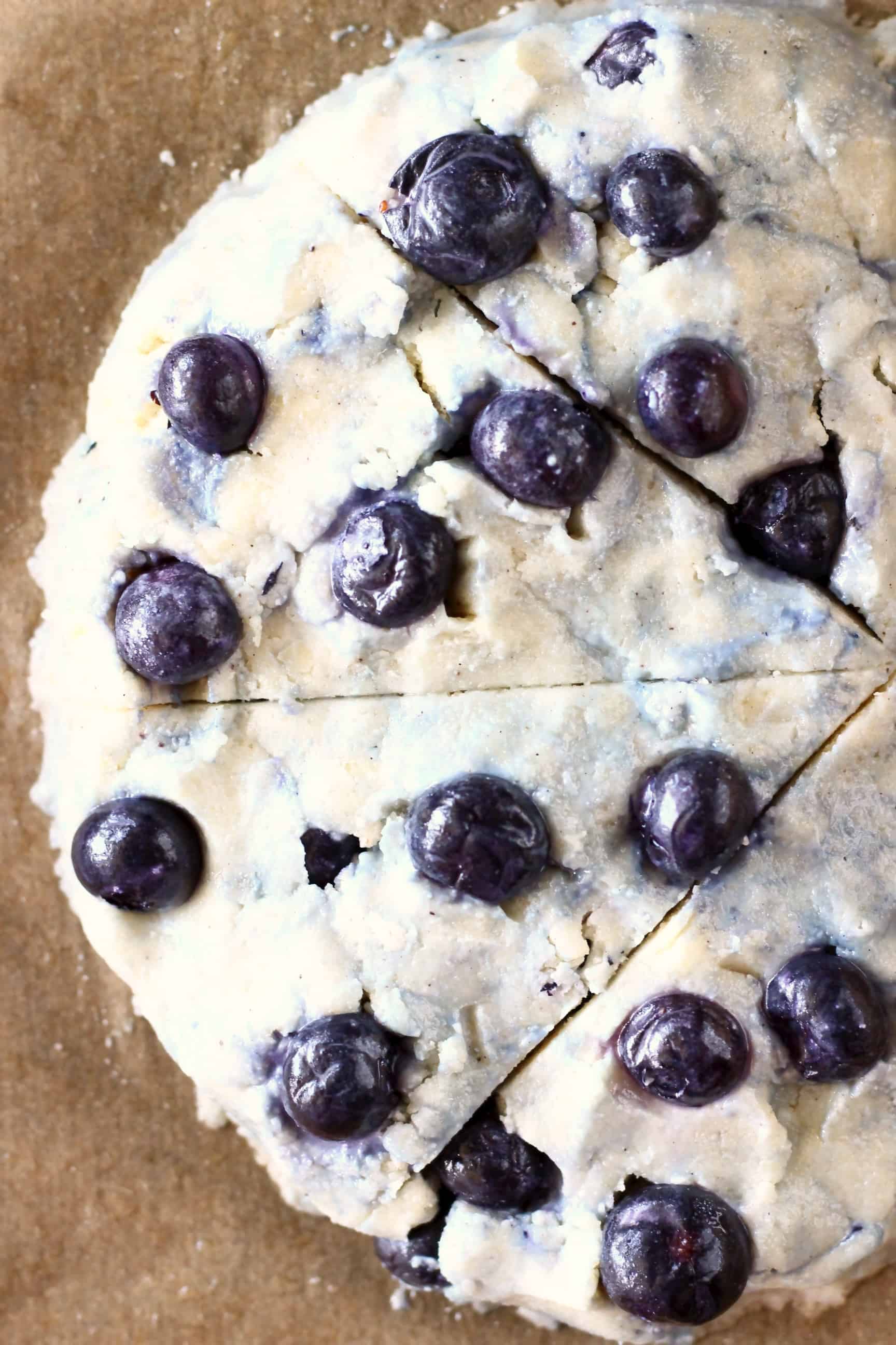 Raw gluten-free blueberry scone dough on a sheet of brown baking paper