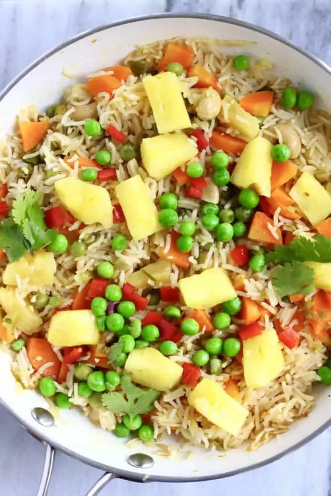 Photo of a saucepan with rice, green peas, carrots and pineapple chunks