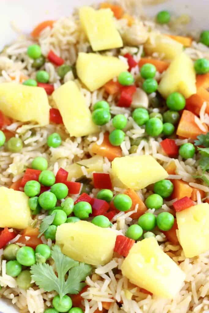 Photo of a saucepan with rice, green peas, carrots and pineapple chunks