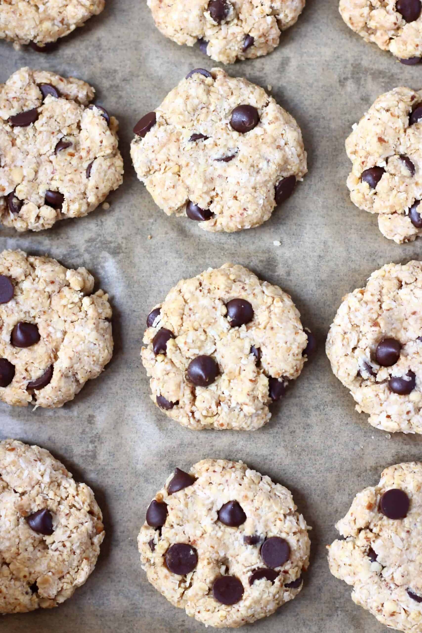 Photo of twelve raw chocolate chip cookies on a piece of brown baking paper