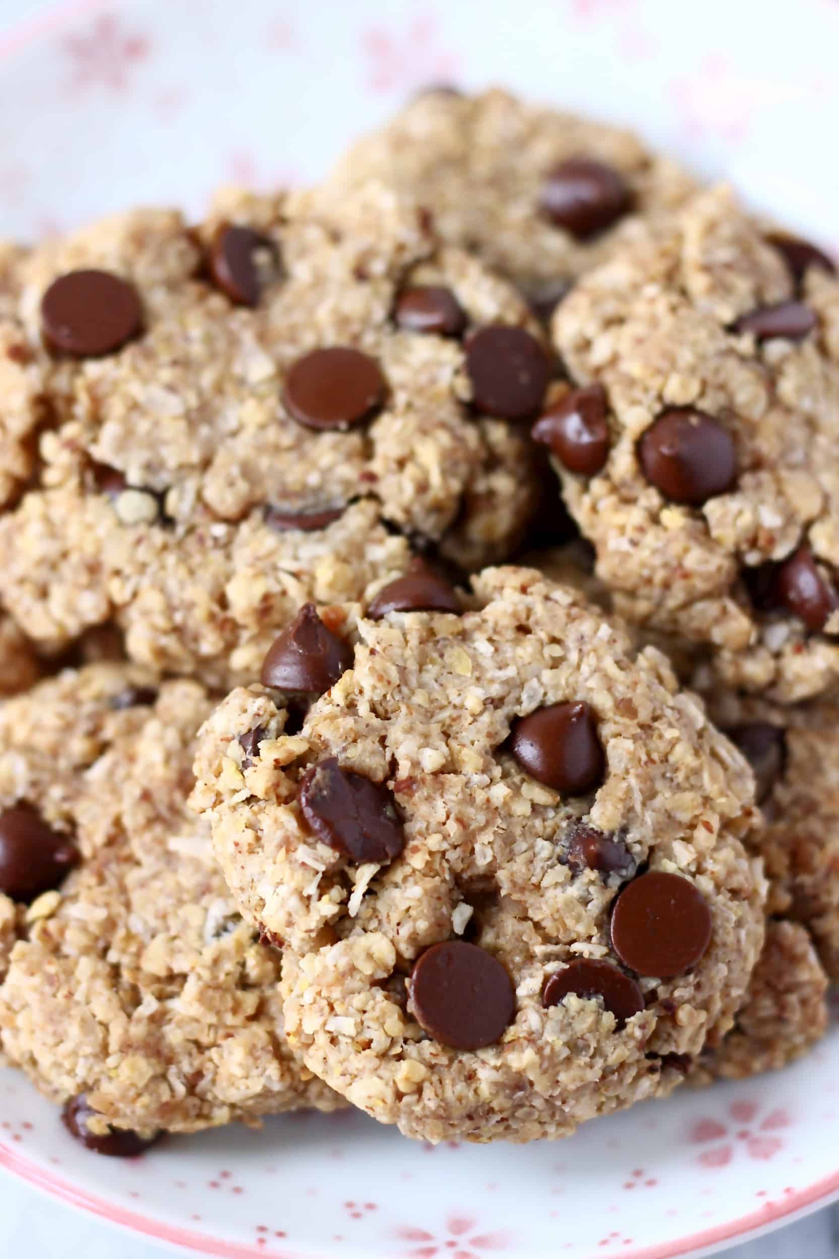 Photo of several chocolate chip cookies on a white plate covered with pink flowers