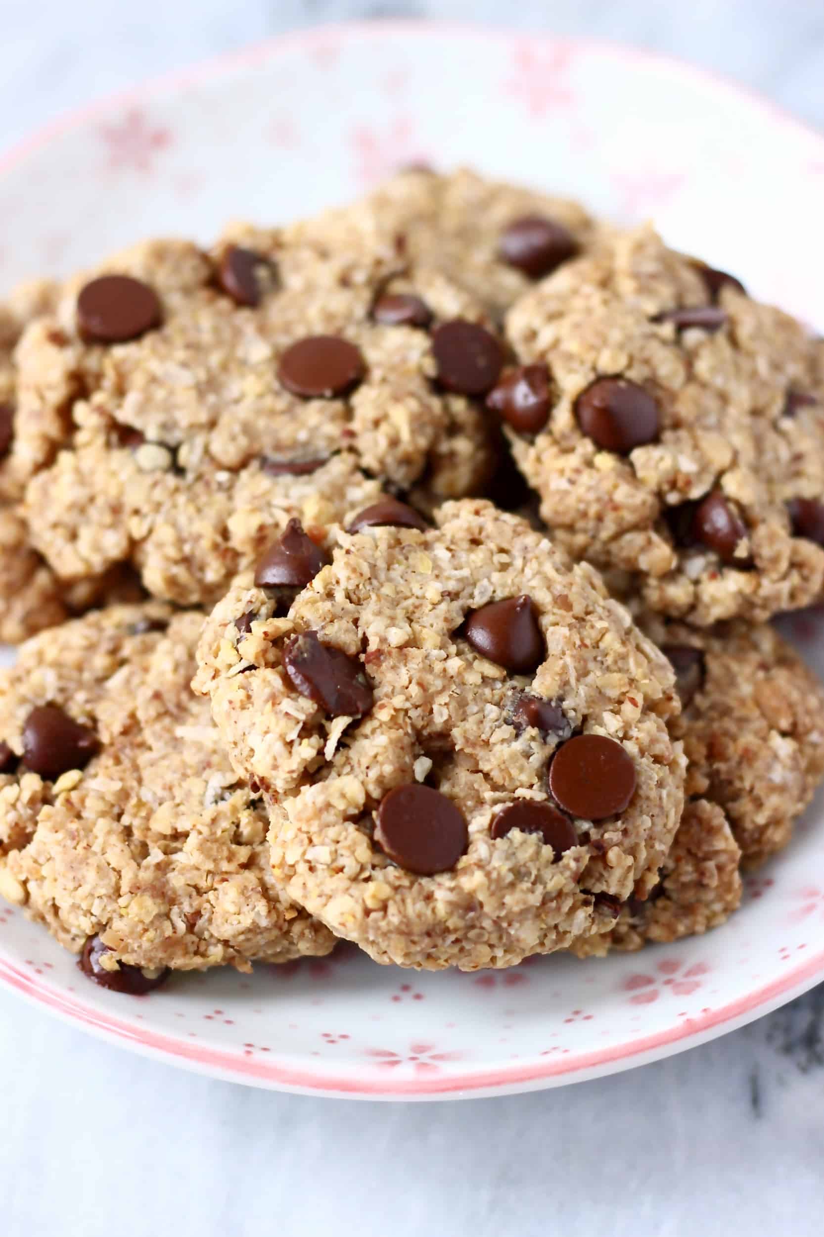 Photo of several chocolate chip cookies on a white plate covered with pink flowers