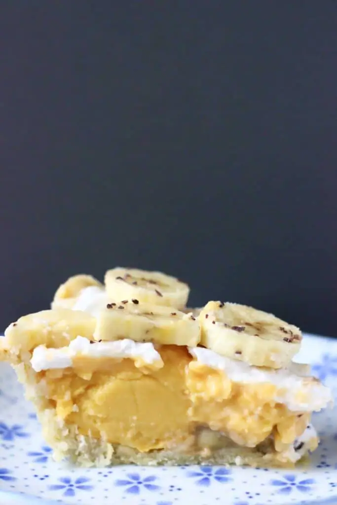 Photo of a slice of banana cream pie on a blue plate with a grey background