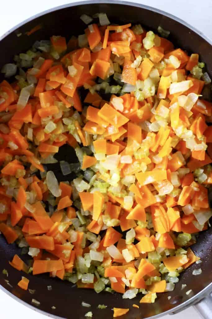 Photo of chopped onion, celery and carrot being cooked in a large saucepan
