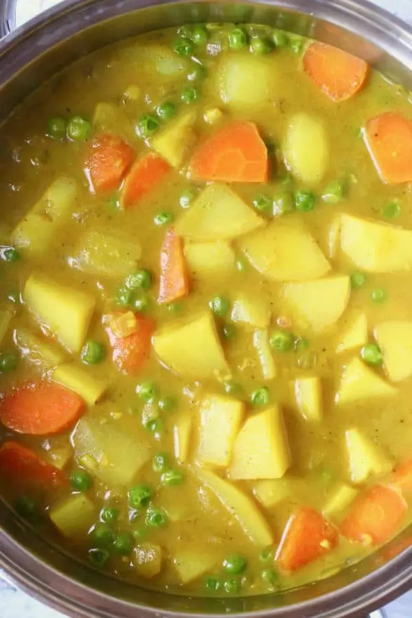 A saucepan with potato, pea and carrot curry