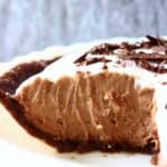A sliced vegan chocolate pie topped with cream and chocolate shavings
