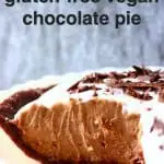 Chocolate pie in a pie dish against a grey fabric background with a slice cut out of it