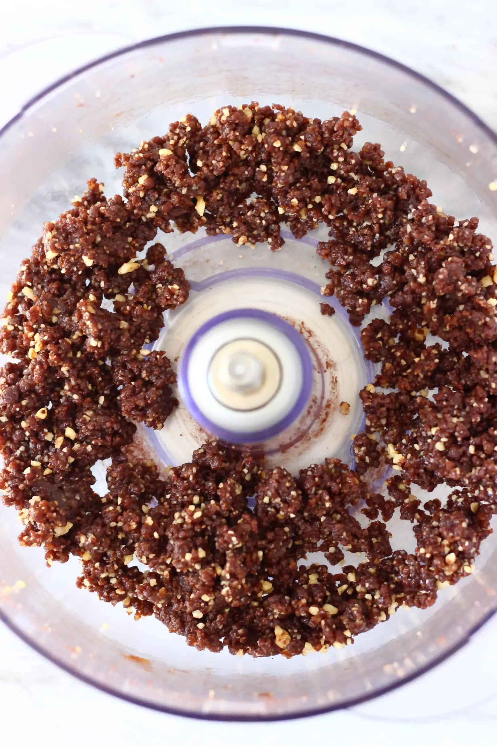 Chocolate pie crust in a food processor against a white background