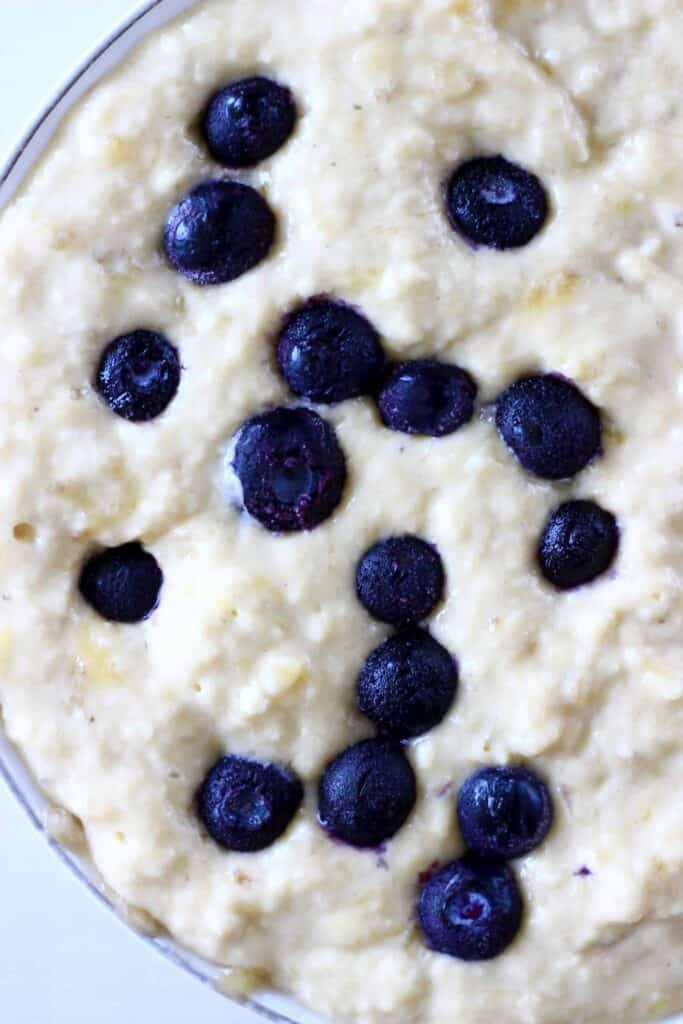 Photo taken from above of sponge cake batter in a bowl dotted with blueberries