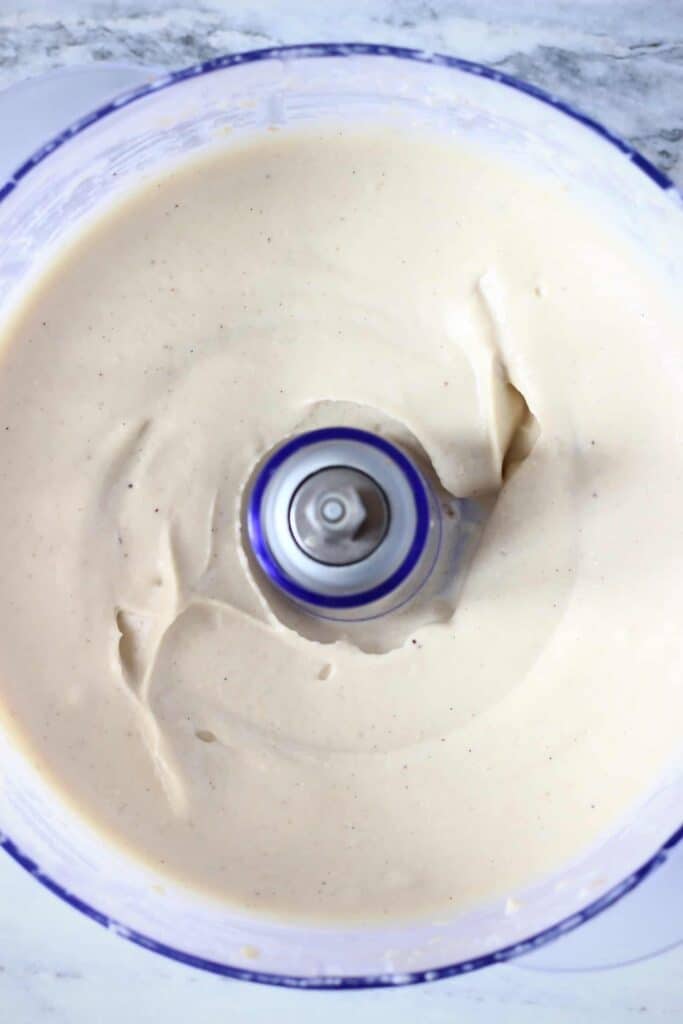 Photo taken from above of a food processor filled with a creamy white pie filling against a marble background