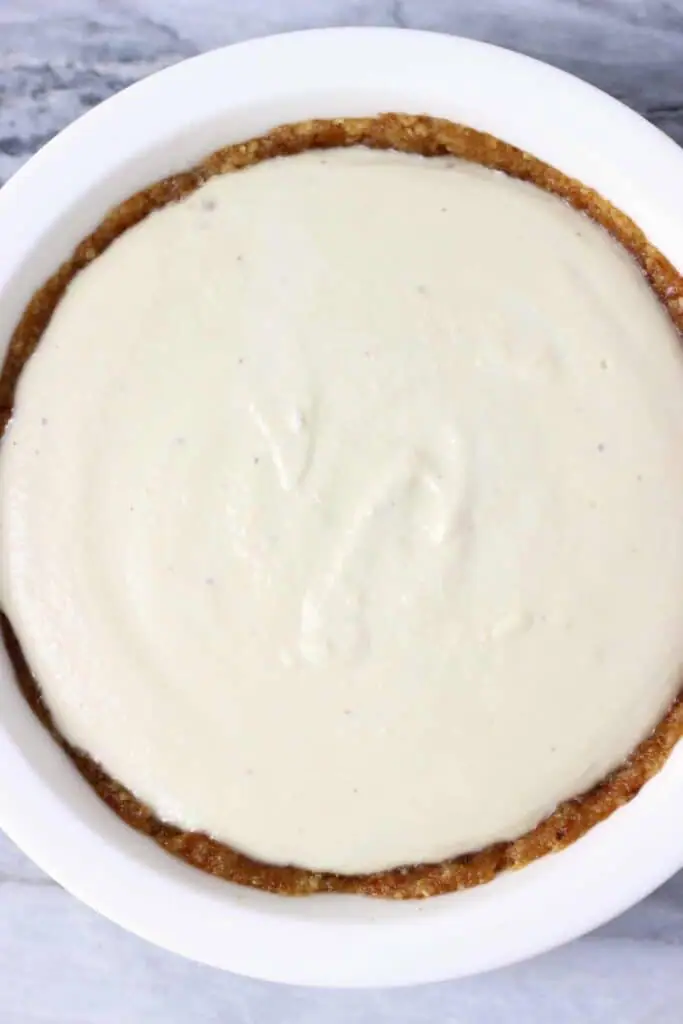 Photo taken from above of a white pie dish with a brown crust and white pie filling against a marble background