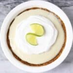 Photo of a pie in a pie dish topped with cream and a lime slice taken from above