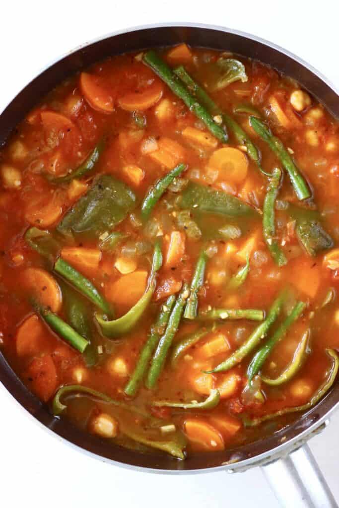 This Vegan Spanish Chickpea Stew is super easy to make, healthy yet satisfying, and packed with veggies! The perfect quick yet nutritious one-pot, plant-based dinner. Gluten-free. #vegan #glutenfree #vegetarian #dairyfree Photo of chickpeas and vegetables in a tomato stew cooked in a saucepan