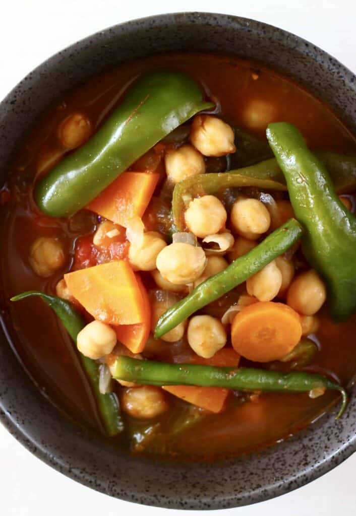 Photo of chickpea and vegetable tomato stew in a grey bowl taken from above