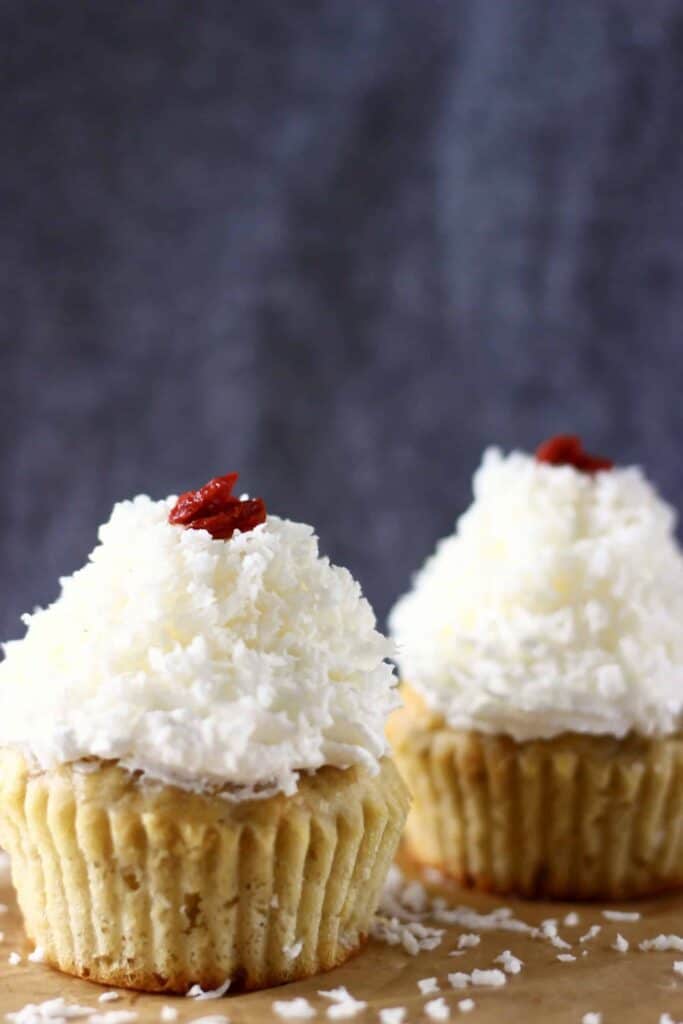 Photo of two cupcakes topped with white frosting against a grey background