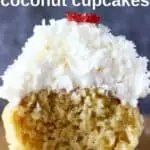 Photo of a cupcake topped with white frosting with a bite taken out of it against a grey background