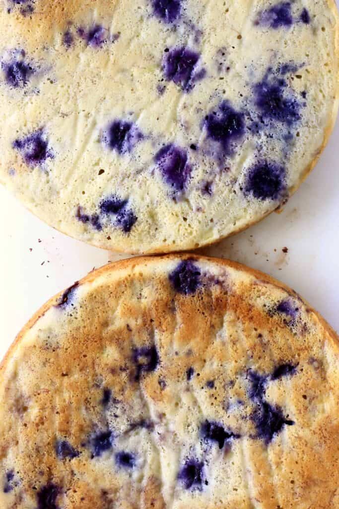 Photo taken from above of two circular blueberry sponges on a white board 