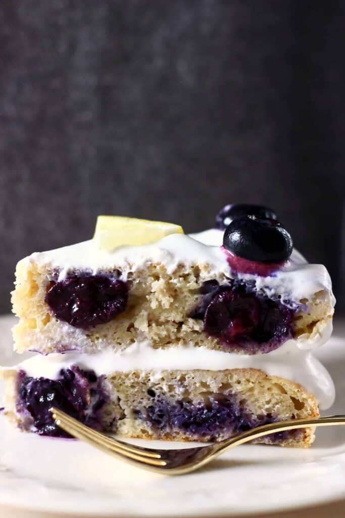 A slice of lemon blueberry layer cake against a grey background