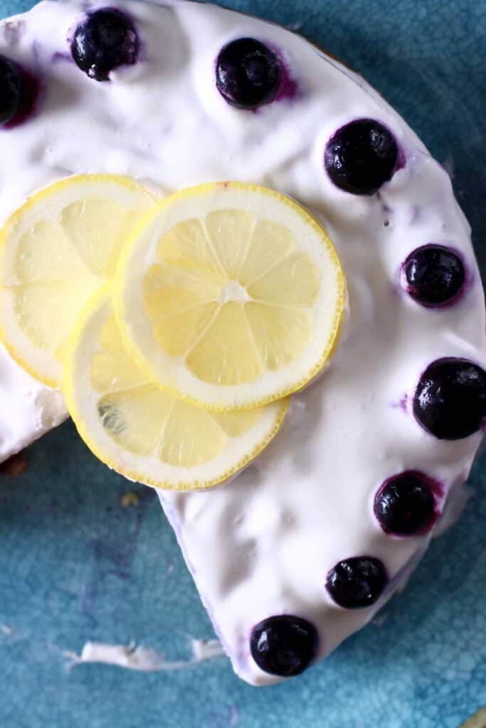 Photo of frosted layer cake taken from above topped with lemon slices and blueberries