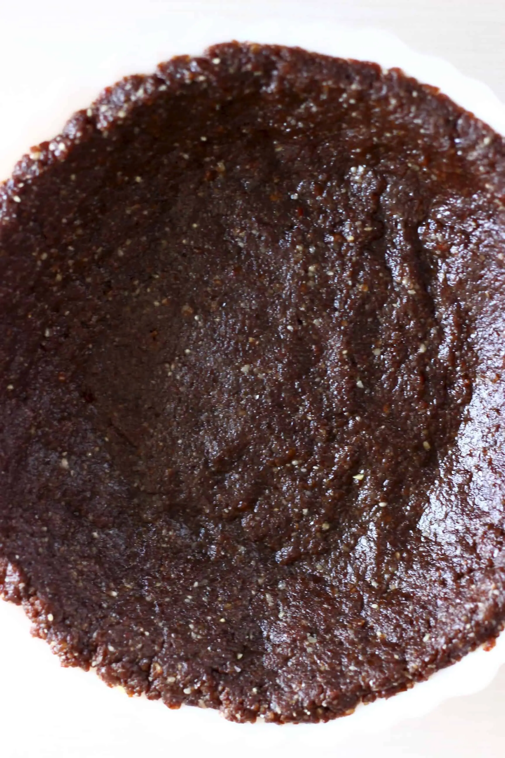 Chocolate pie crust in a white pie dish against a white background