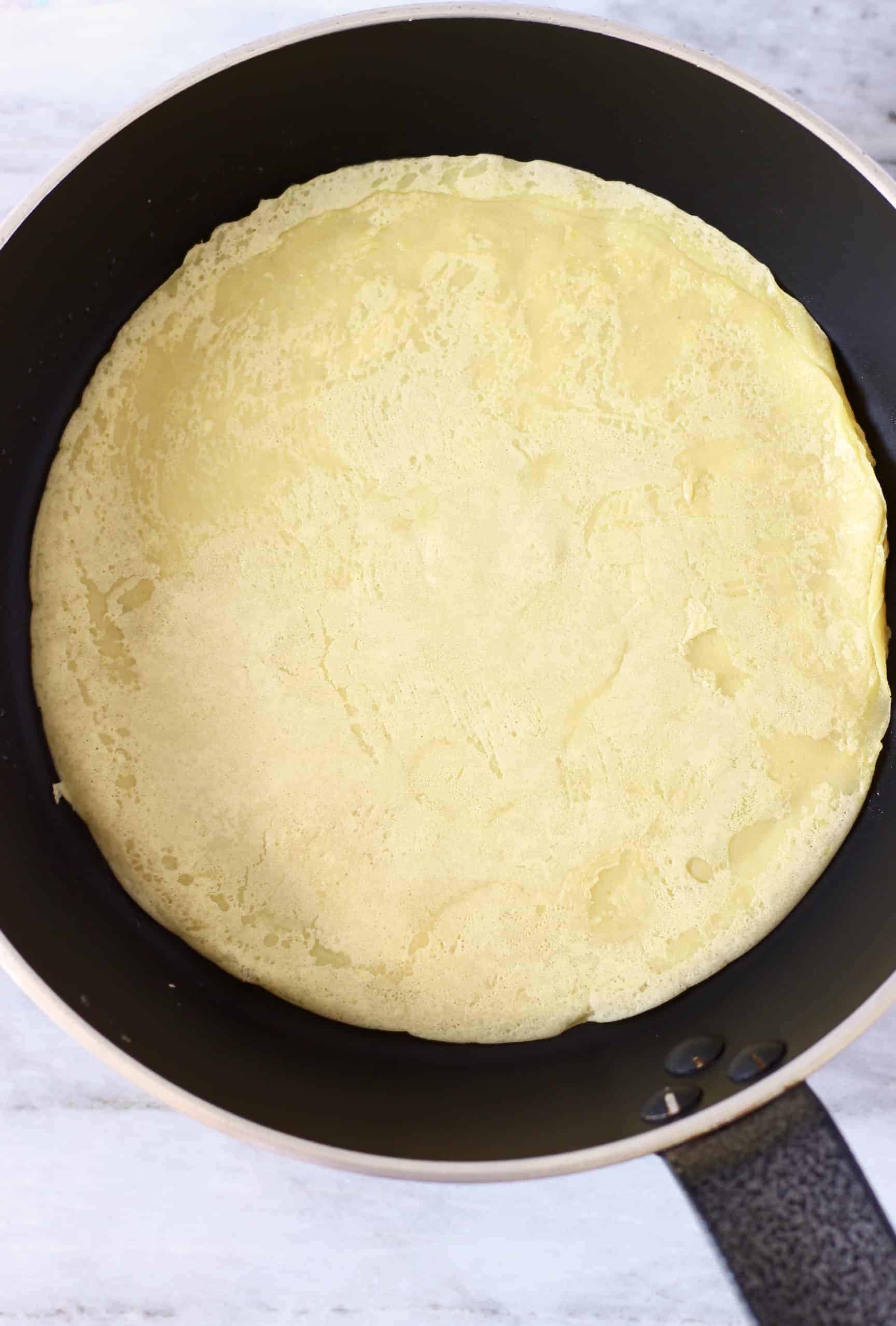 A round yellow-coloured wrap in a frying pan