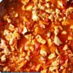 Photo of tofu crumbles in a red bolognese sauce in a large saucepan taken from above