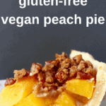 Photo of a slice of peach pie on a white plate with a gold fork and a grey background