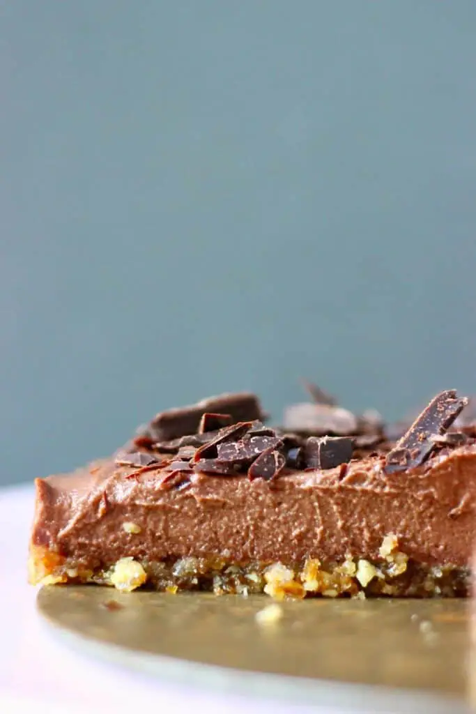 Photo of a sliced chocolate cheesecake topped with dark chocolate shavings against a grey background