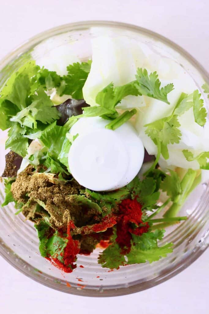 These Vegan Eggplant Carnitas Tacos are full of flavour, seriously meaty, and really satisfying. They're a great healthy, vegetarian, plant-based dinner option for Mexican night! #vegan #glutenfree #tacos #vegetarian #rhiansrecipes #mexican Photo of raw onion, fresh herbs and spices in a food processor taken from above