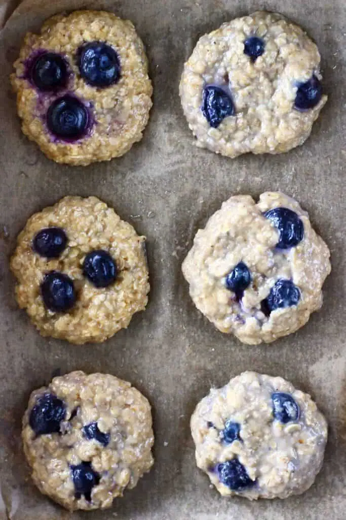 Six uncooked blueberry cookies on a brown piece of baking paper