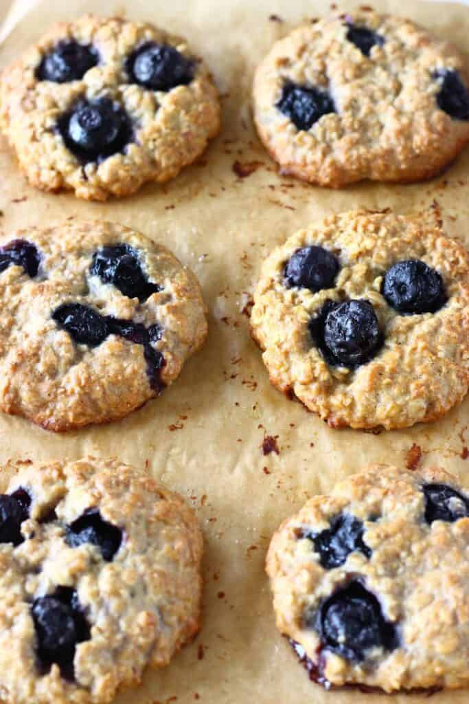 Six blueberry cookies on a brown piece of baking paper