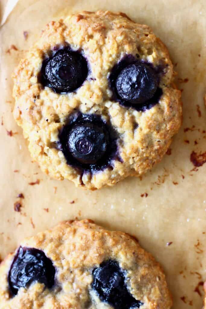 Two blueberry cookies on a brown piece of baking paper