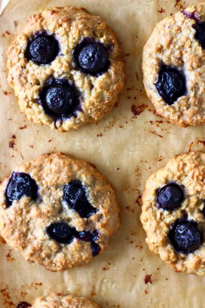Four blueberry cookies on a brown piece of baking paper