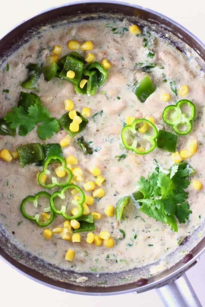 Photo of a saucepan with white stew with white beans, sweetcorn and green pepper
