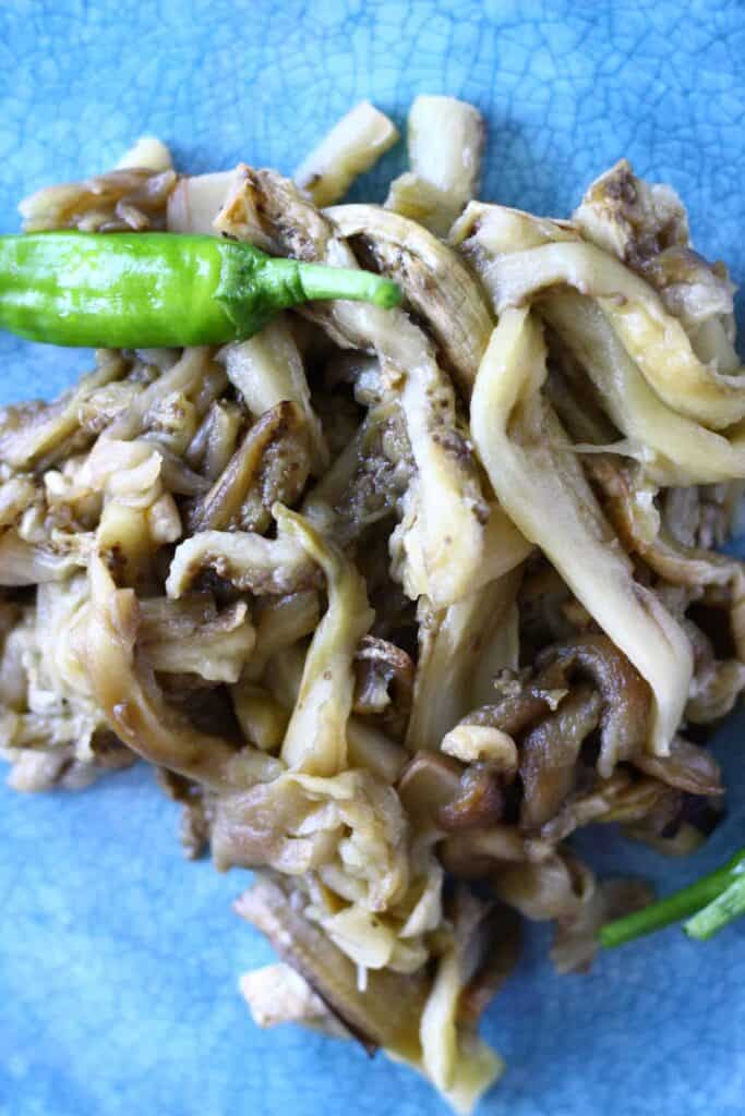 These Vegan Eggplant Carnitas Tacos are full of flavour, seriously meaty, and really satisfying. They're a great healthy, vegetarian, plant-based dinner option for Mexican night! #vegan #glutenfree #tacos #vegetarian #rhiansrecipes #mexican Photo of shredded roasted eggplant on a blue plate