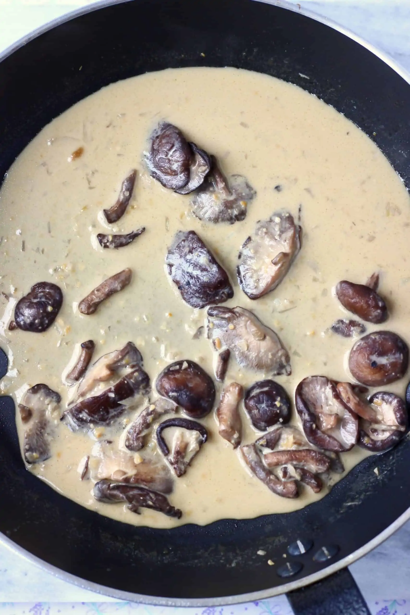 Garlic, shiitake mushrooms, almond milk and miso in a black frying pan