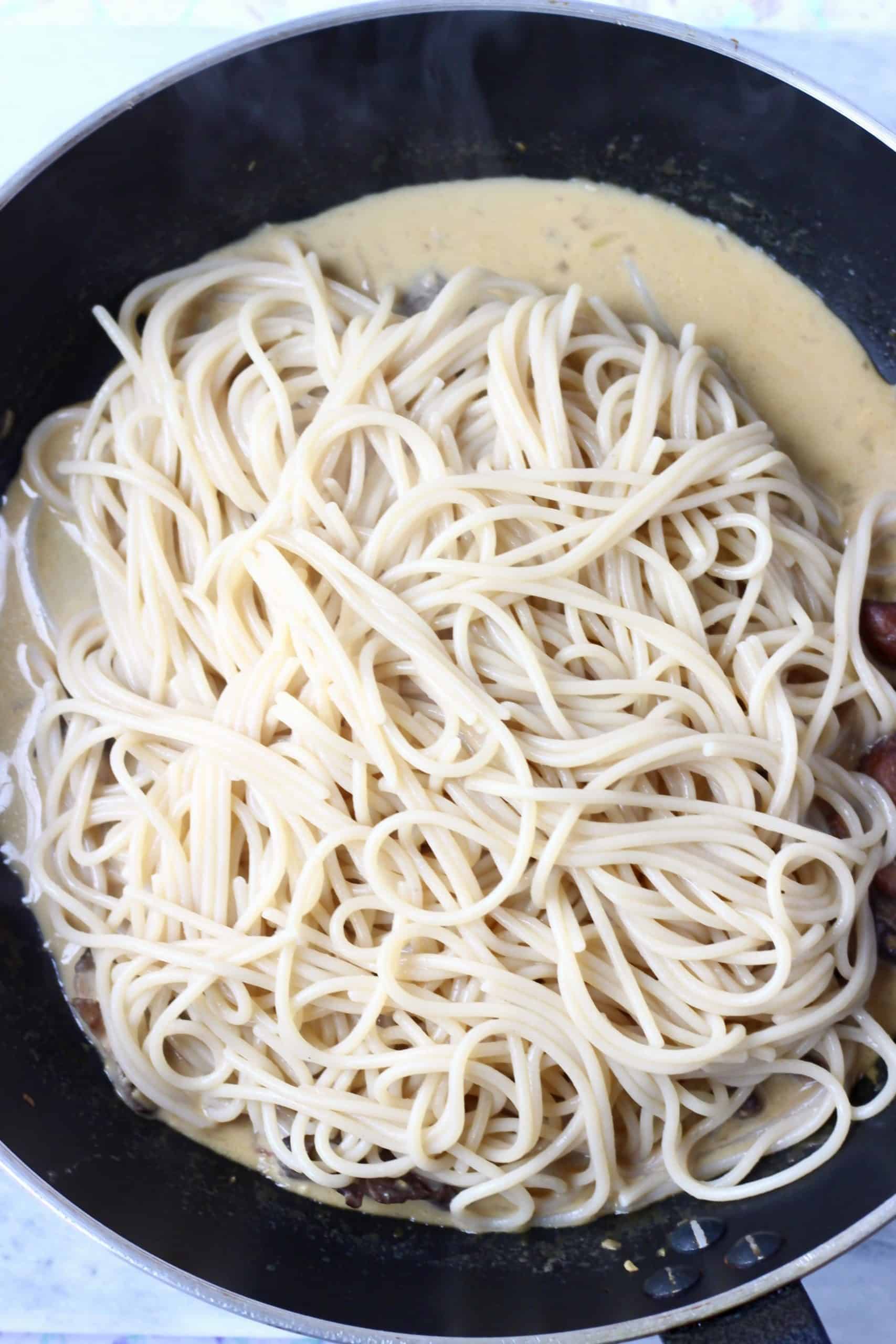 Creamy vegan miso pasta sauce with spaghetti in a black frying pan