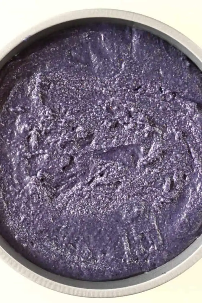 Photo of a deep purple cake batter in a silver baking tin against a white background