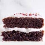 Photo of a slice of purple sponge cake with light purple frosting against a grey marble background