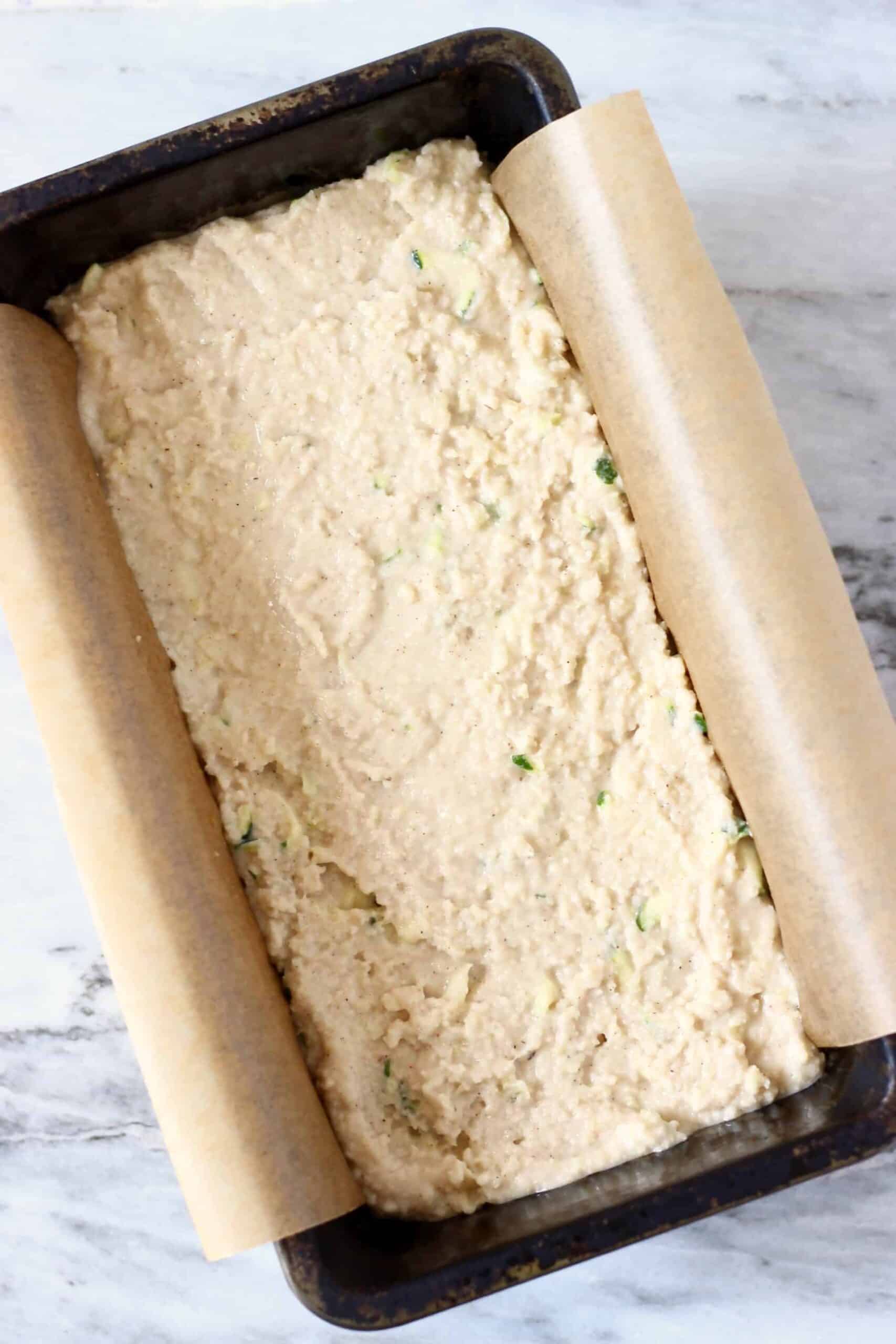 This Gluten-Free Vegan Zucchini Bread is seriously moist, perfectly dense and subtly fragrant. It's made with grated zucchini and subtly spiced with cinnamon for a warm, toasty flavour. It makes the perfect dessert, breakfast, brunch or snack, especially for autumn/fall. #vegan #dairyfree #rhiansrecipes #zucchinibread #glutenfree #baking Raw gluten-free vegan zucchini bread batter in a loaf tin lined with baking paper