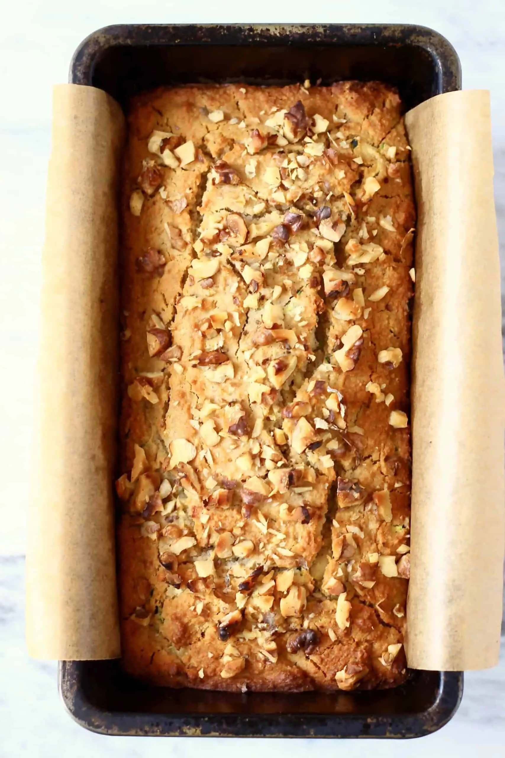 A loaf of gluten-free vegan zucchini bread in a loaf tin lined with baking paper