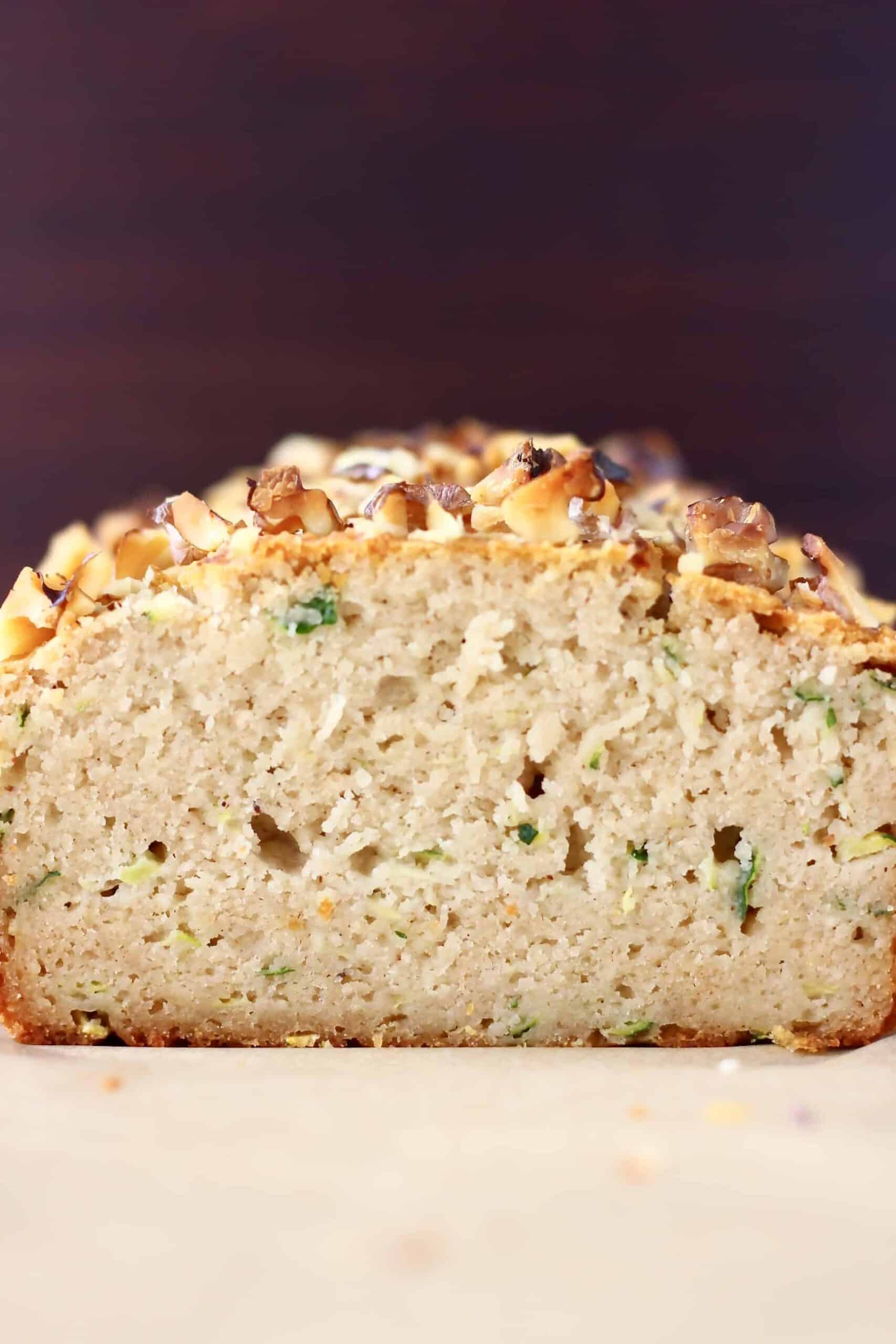 This Gluten-Free Vegan Zucchini Bread is seriously moist, perfectly dense and subtly fragrant. It's made with grated zucchini and subtly spiced with cinnamon for a warm, toasty flavour. It makes the perfect dessert, breakfast, brunch or snack, especially for autumn/fall. #vegan #dairyfree #rhiansrecipes #zucchinibread #glutenfree #baking A sliced loaf of gluten-free vegan zucchini bread