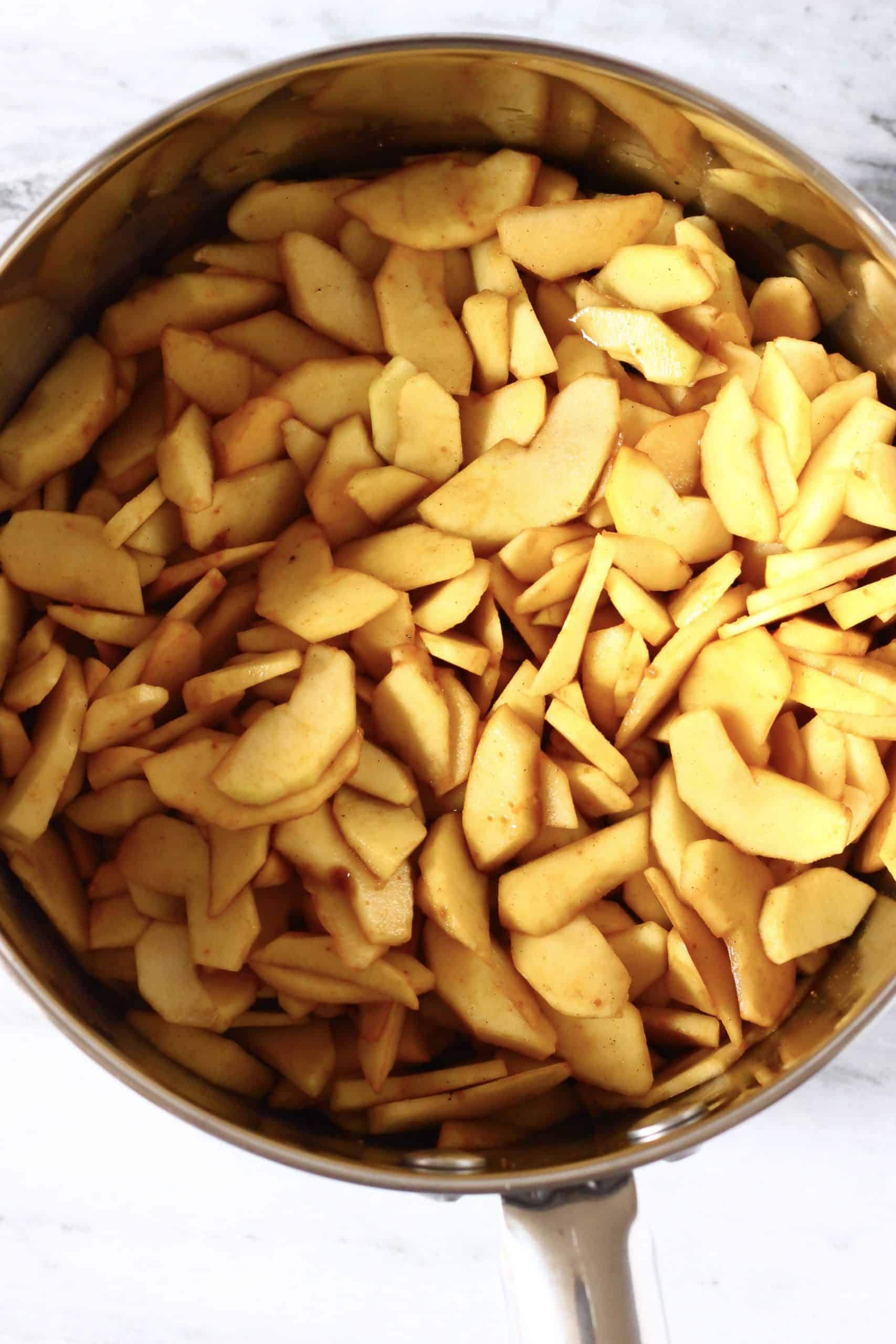 Sliced apples with coconut sugar and spices in a silver pan